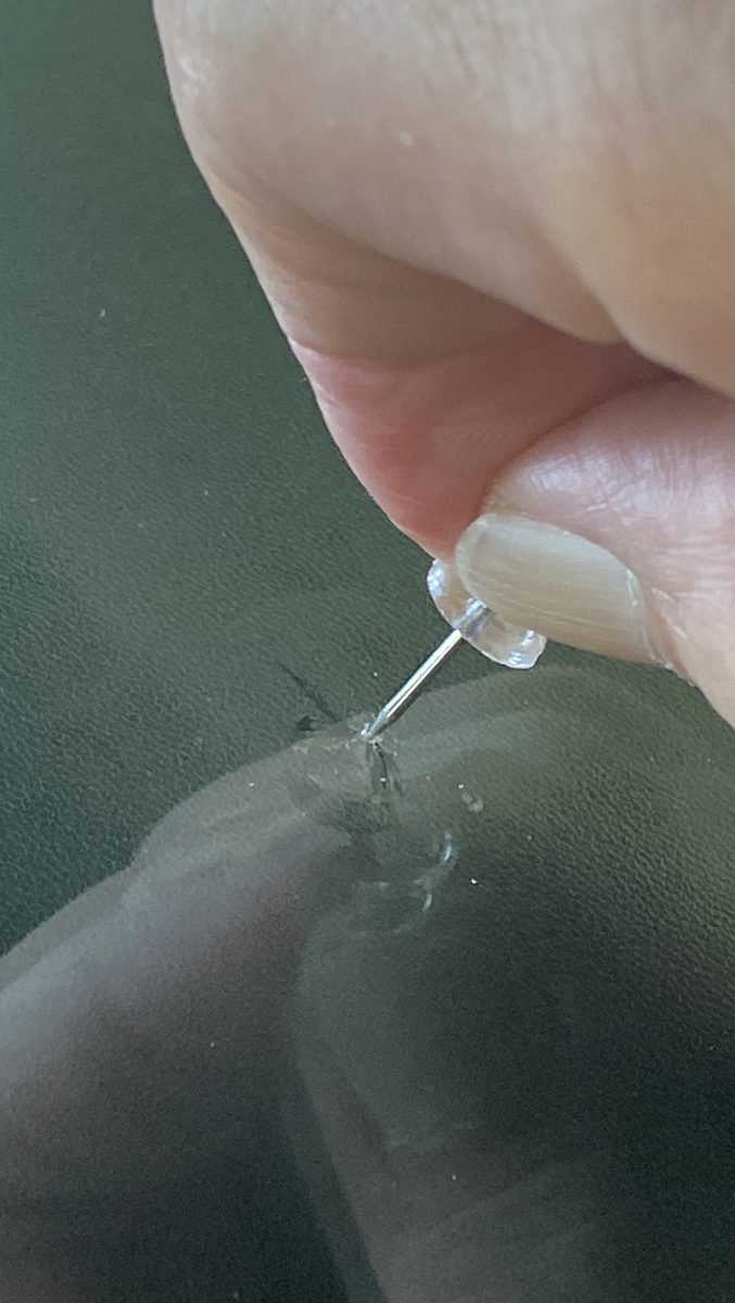 付属のピンでフロントガラスの飛び石キズの中に残ったガラス片を取り除いている様子