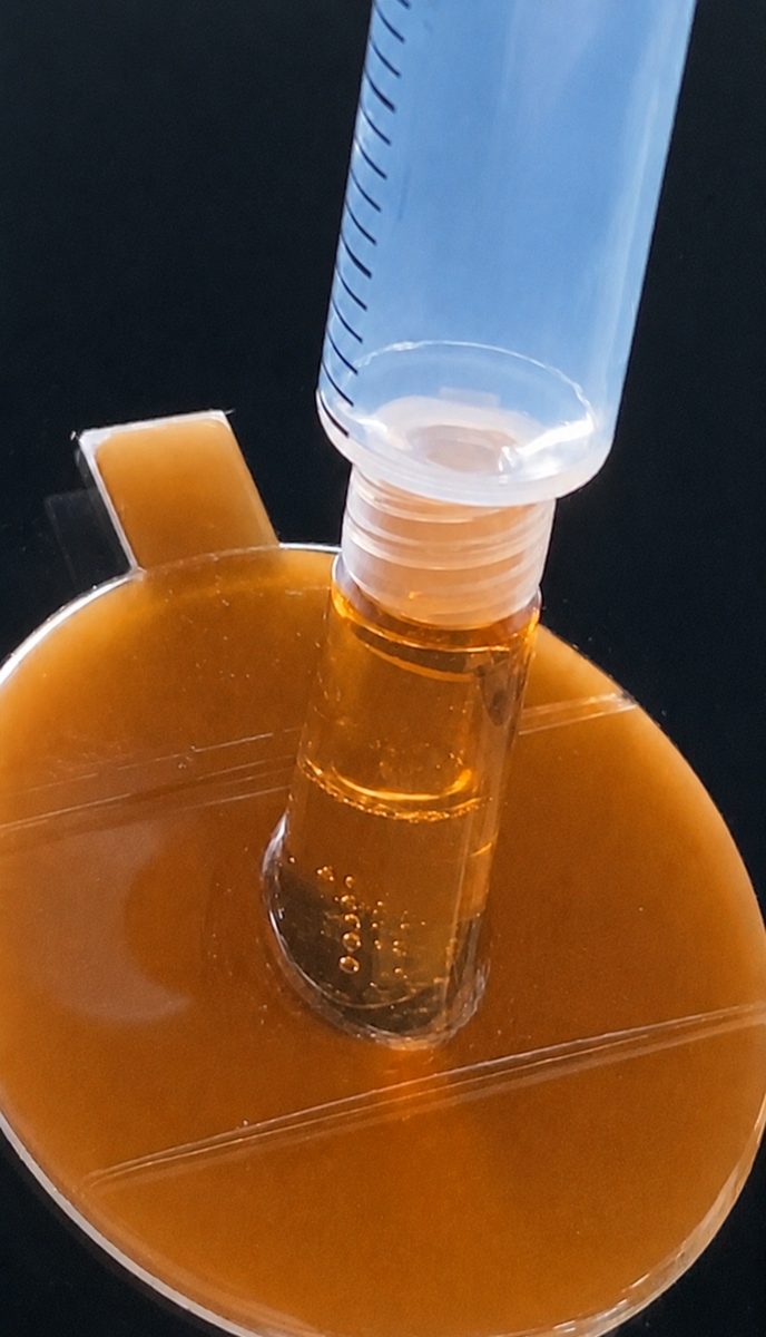 L-99の注射器を台座に取り付けてエア抜きをしている様子。補修液の中に気泡が見える