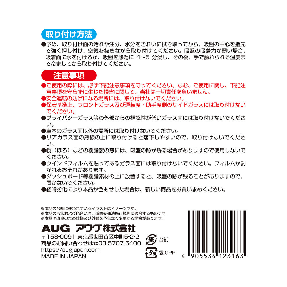 台紙裏面の右側。取り付け方法は、取り付け面を拭き取り、吸盤の中心を押し付けて空気を抜く。吸着力が弱いときは水を付けるか熱湯に4〜5分浸して冷ましてから貼る。注意事項として、安全運転の妨げになる場所には取り付けないこと、経時劣化で色あせた場合は新しい商品に取り替えることなど。アウグ株式会社の連絡先と MADE IN JAPAN の表示