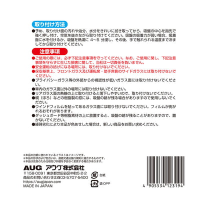 台紙裏面の右側。取り付け方法は、取り付け面を拭き取り、吸盤の中心を押し付けて空気を抜く。吸着力が弱いときは水を付けるか熱湯に4〜5分浸して冷ましてから貼る。注意事項として、安全運転の妨げになる場所には取り付けないこと、経時劣化で色あせた場合は新しい商品に取り替えることなど。アウグ株式会社の連絡先と MADE IN JAPAN の表示